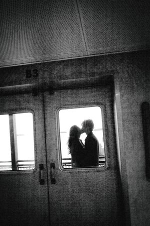 Romantic silhouette of a couple kissing framed in a ferry window in black and white photography.