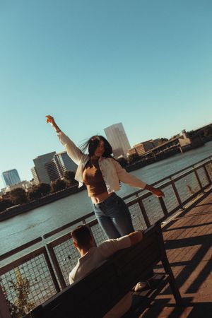 Silhouette of dancer performing graceful movements against urban waterfront backdrop during golden hour.