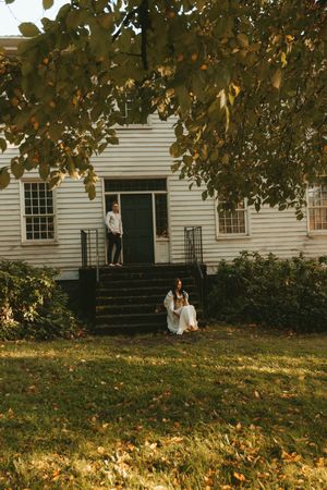 A white colonial house with autumn leaves scattered across the lawn in warm golden sunlight.