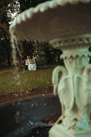 A series of blurred photos showing a couple sitting on grass with a decorative stone railing in the foreground.