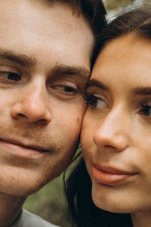 Close-up portrait of a couple with warm smiles in soft lighting.