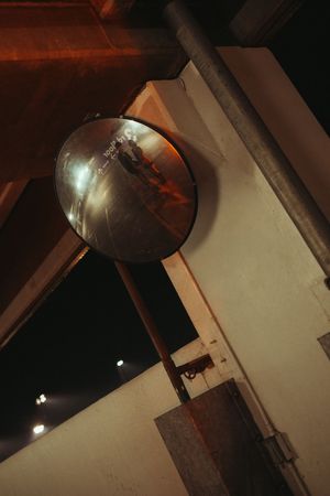 A series of dark photos showing an industrial lamp fixture mounted on a white wall in dim lighting conditions.