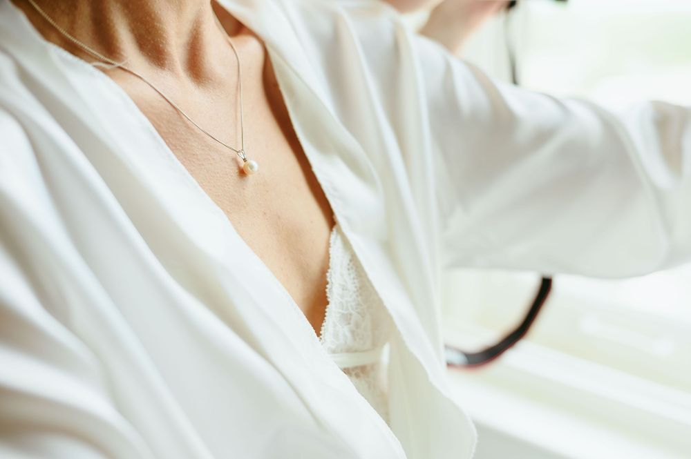 Three close-up photos showing delicate gold chain necklace details on white fabric background.