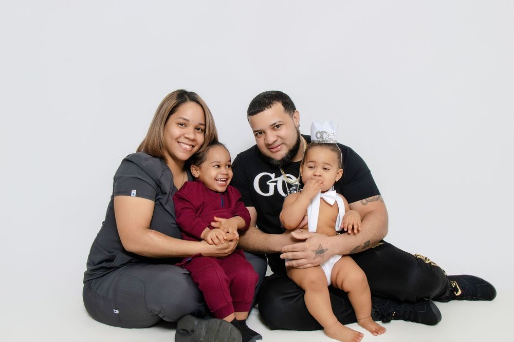 Family lying together on white background in casual outfits.