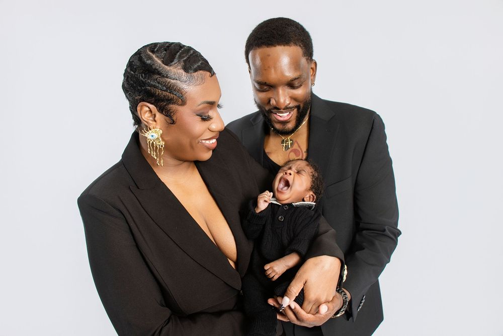 Elegant family portrait with parents in black formal wear.
