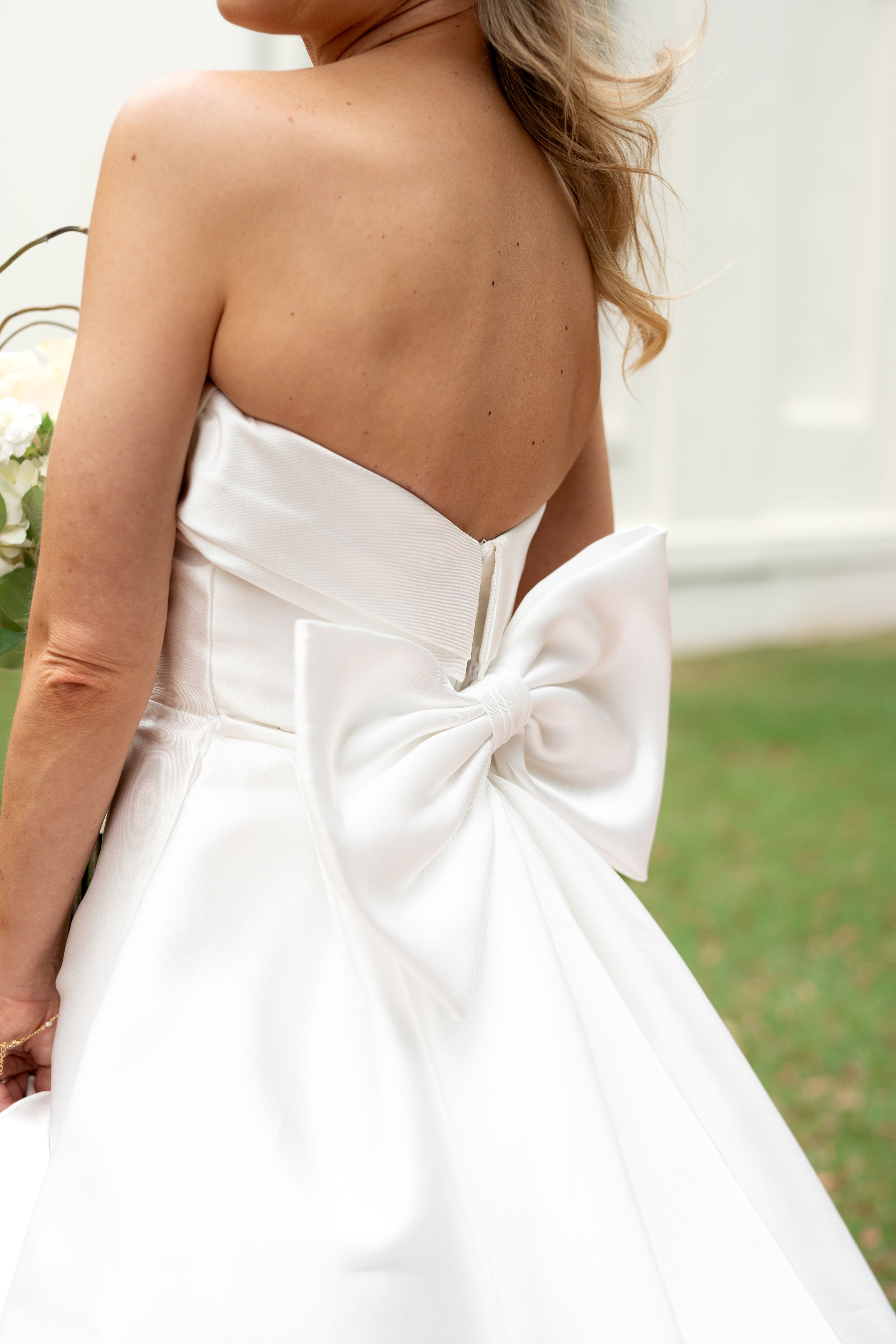 Details of a white wedding dress showing bow and fabric texture.