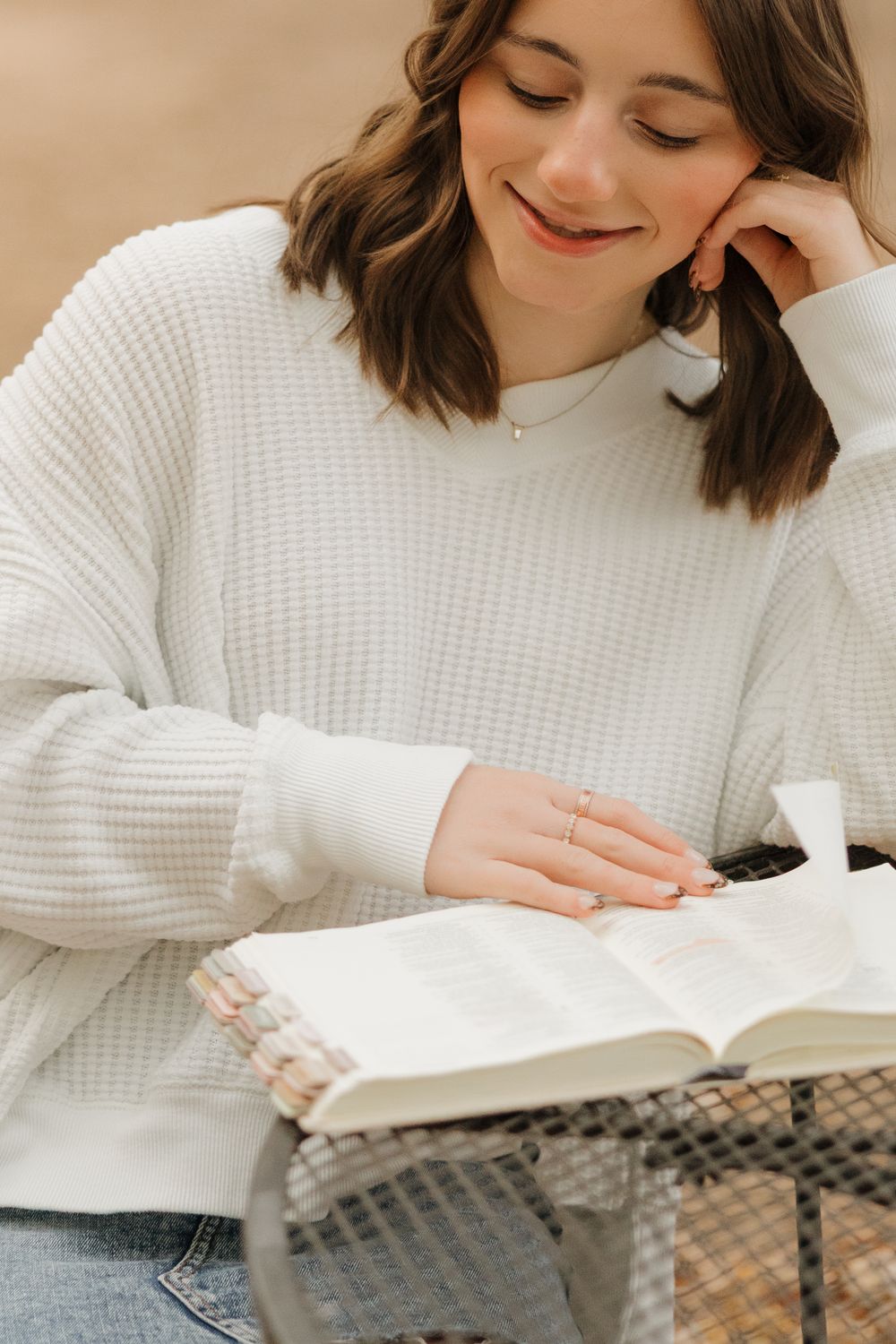 Person wearing white sweater reading a book while relaxing on a cozy couch.