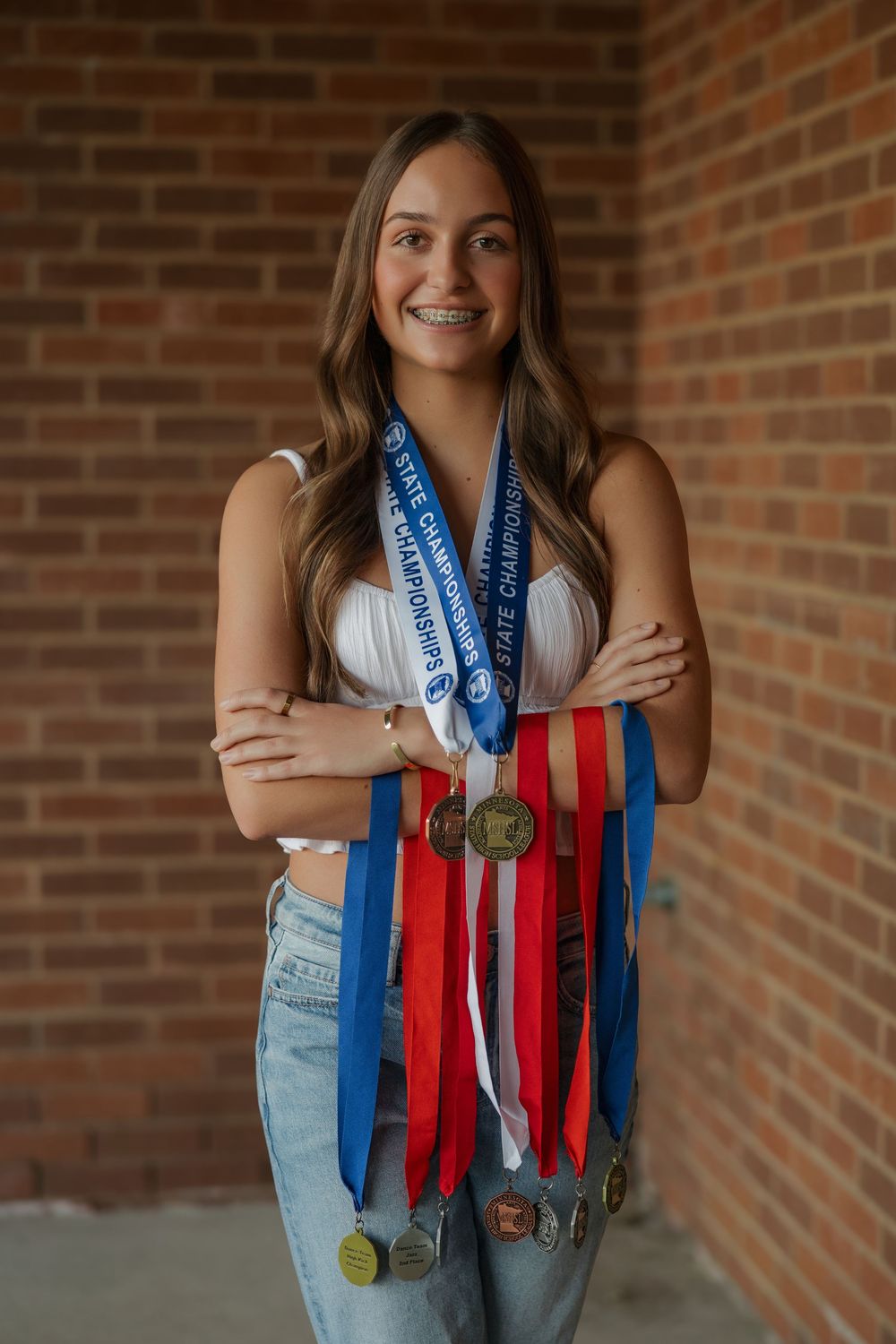 A series of five similar photos showing an athlete displaying medals against a brick wall background while wearing jeans.