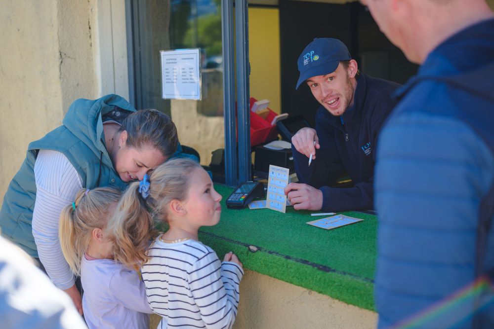 Players gathered around a mini golf putting area under yellow awnings.
