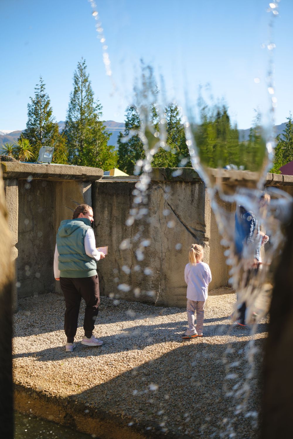 People playing mini golf viewed through a decorative water feature.