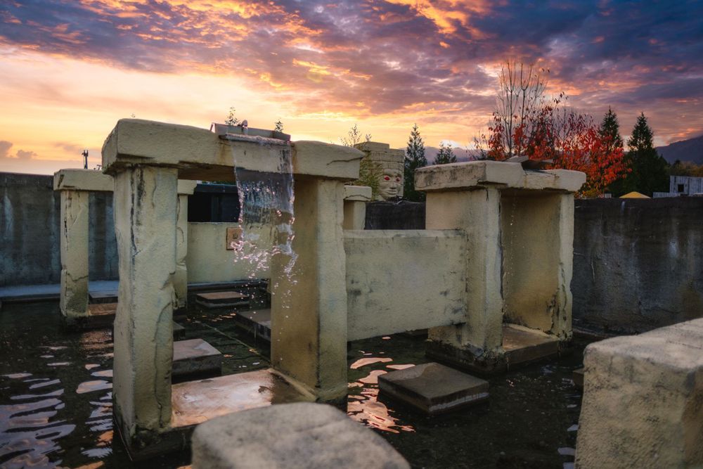 Dramatic sunset sky with orange clouds over concrete buildings and structures.