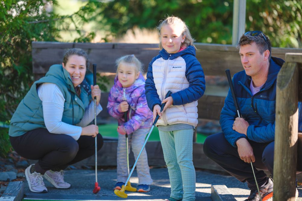 Group playing mini golf on an outdoor course with artificial turf.