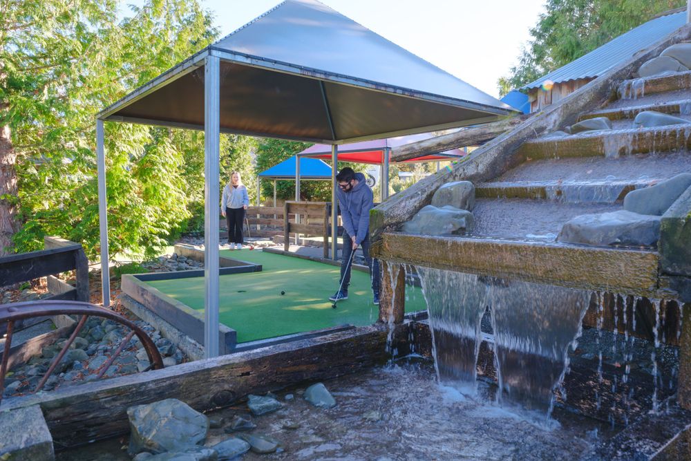 Miniature golf course with water features and wooden bridges under blue sky.