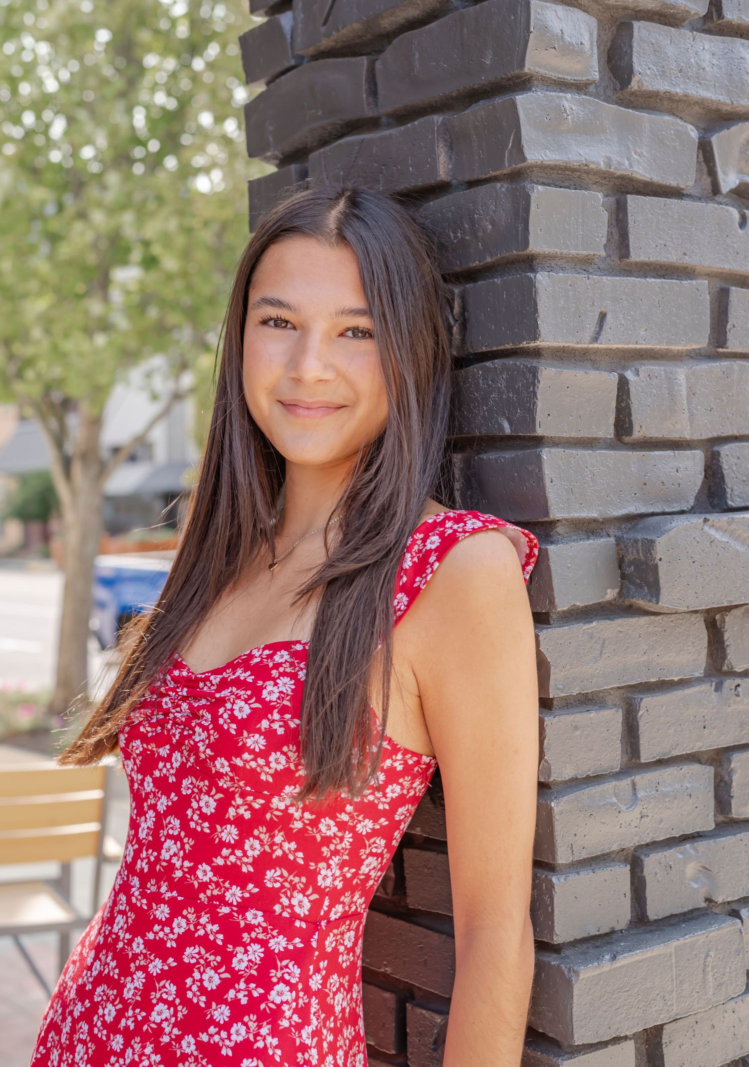 A summer portrait against dark brick architecture with natural lighting.