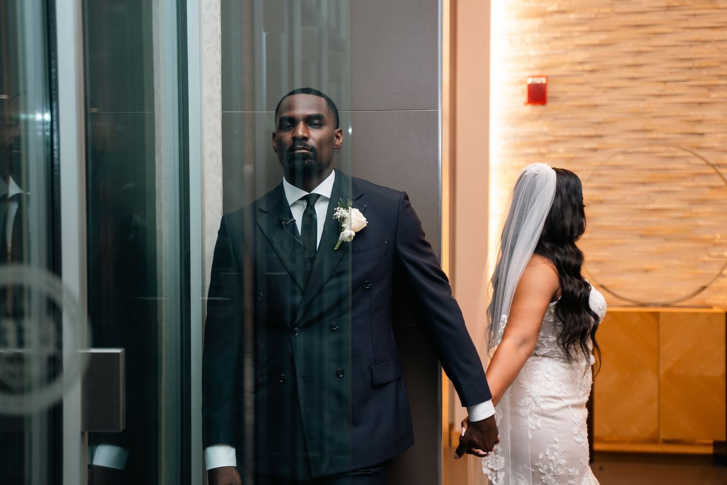 Elegant wedding couple shares a tender first look moment in a hotel hallway.