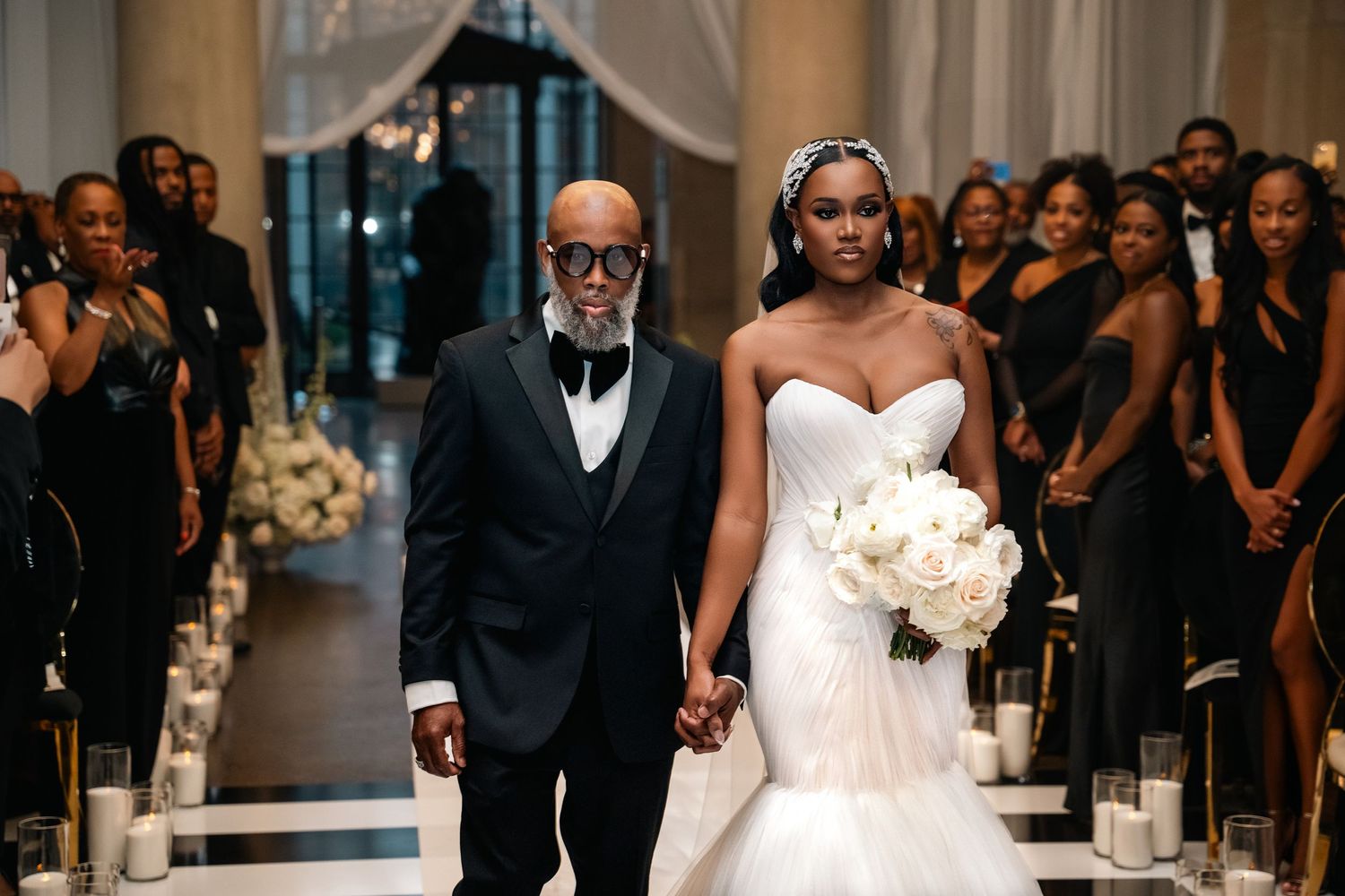 Wedding ceremony in grand hall with bride walking down aisle in stunning mermaid gown.