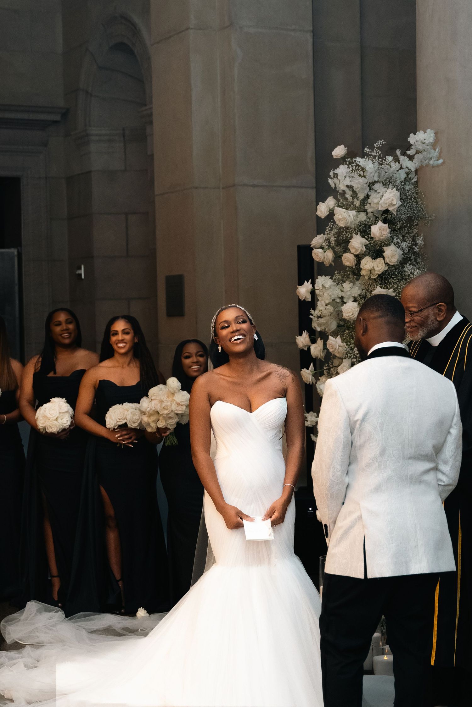 Joyful wedding ceremony moment with attendants in black dresses and floral decorations.