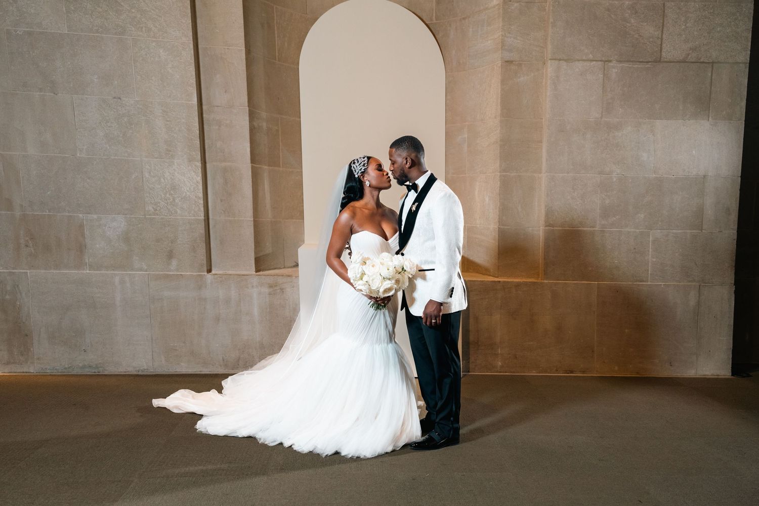 Romantic wedding portrait under stone archway with flowing white gown.