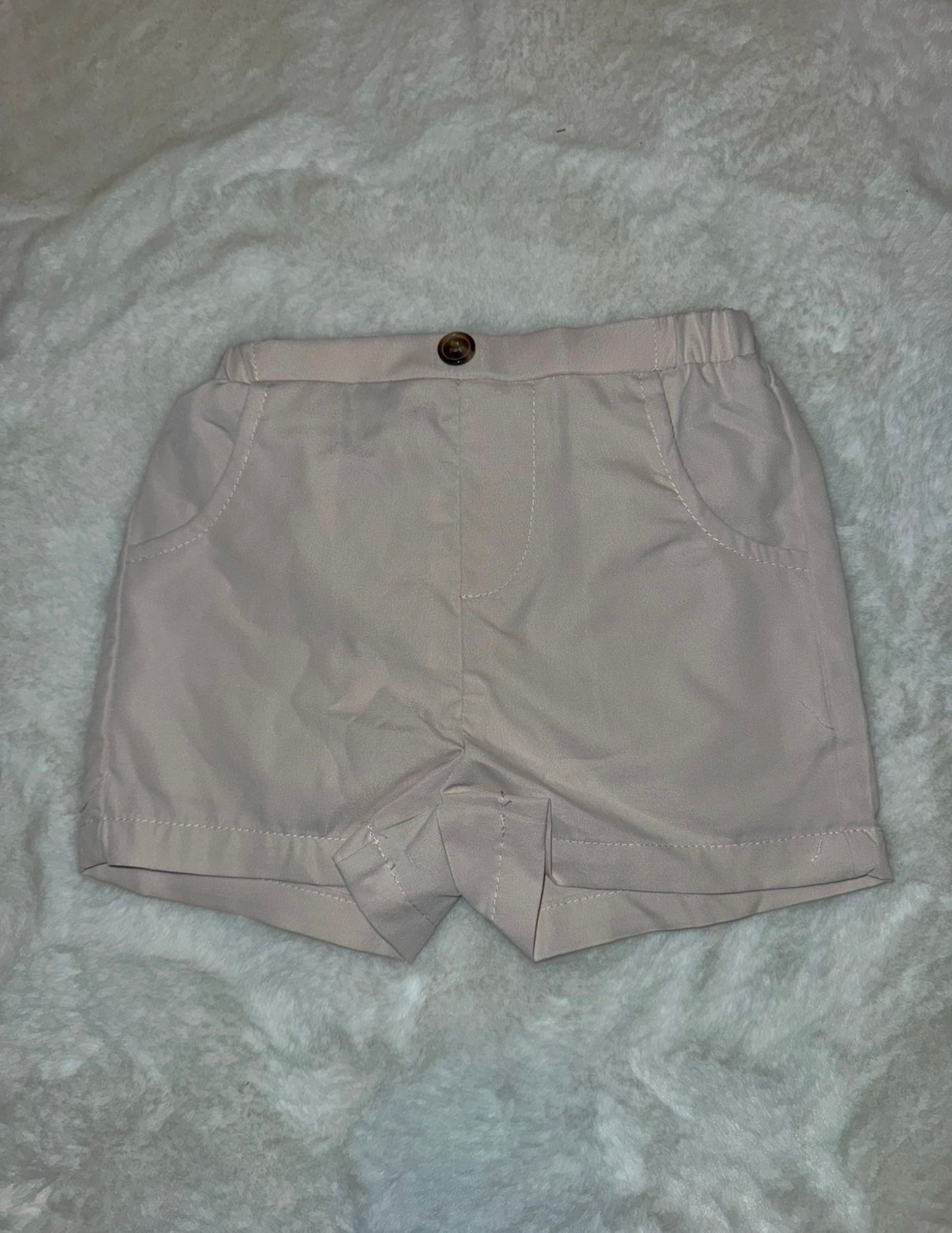 Light beige cotton shorts with elastic waistband shown on white background.