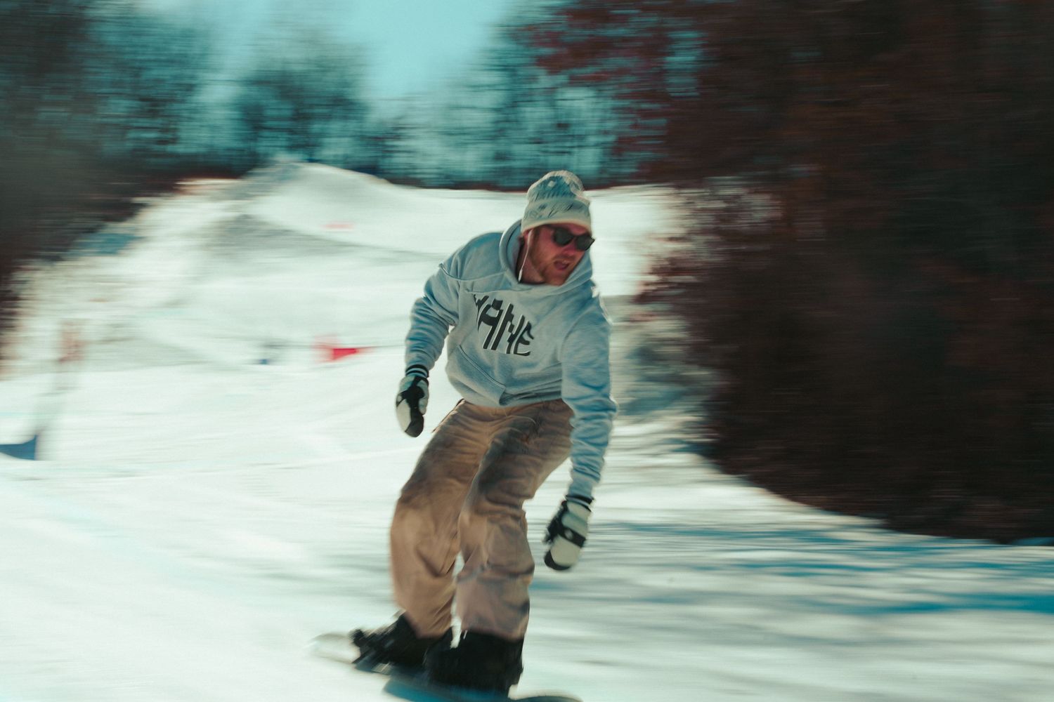 A snowboarder carves down a snowy slope in motion-blurred action shot.
