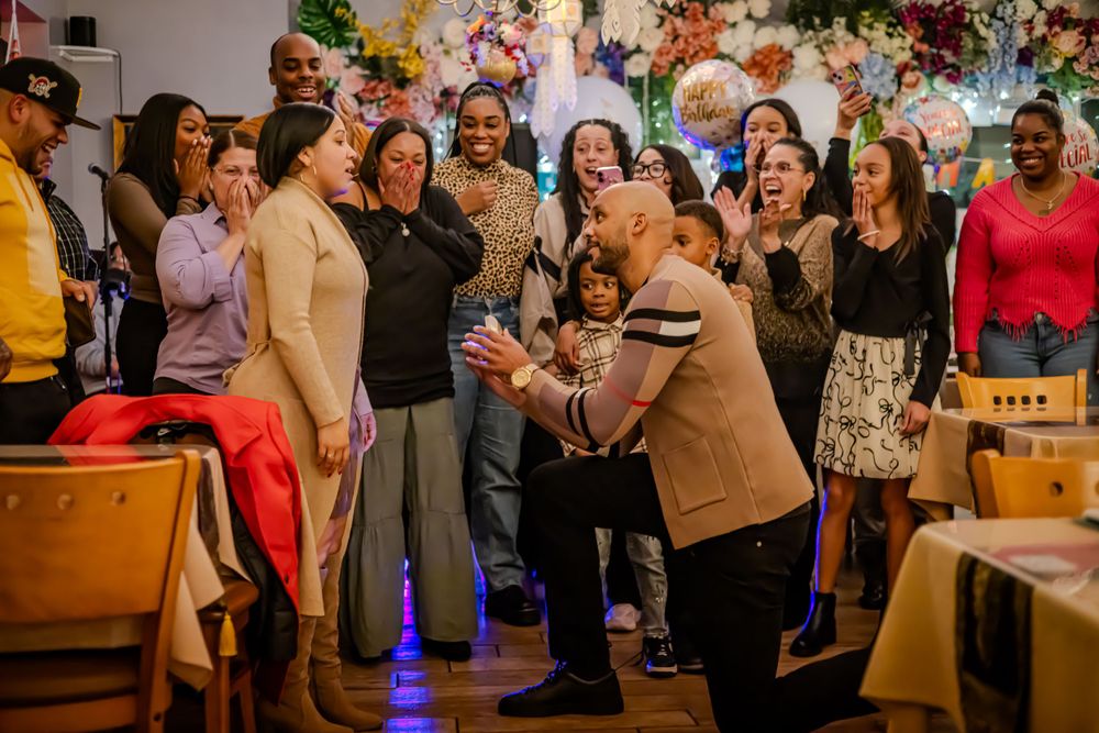 A lively group of people dancing and celebrating together at what appears to be a festive indoor party or gathering.