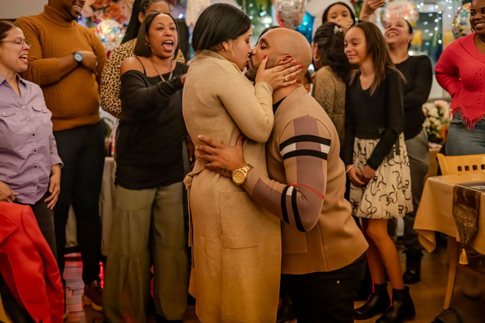 A joyful crowd of people laughing and celebrating at an indoor gathering wearing casual fall attire.