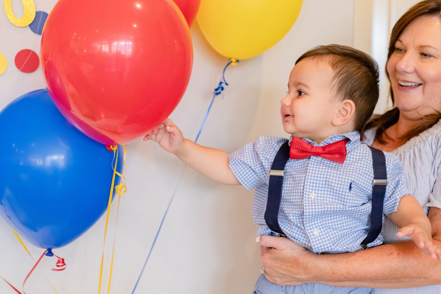 A joyful celebration scene with colorful balloons featuring red, blue and yellow decorations against a white background.
