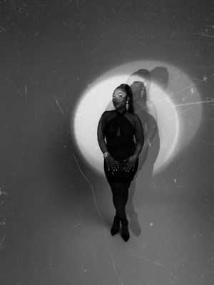 Artistic black and white portrait of a silhouetted figure against a luminous circular backdrop creating a dramatic shadow effect.