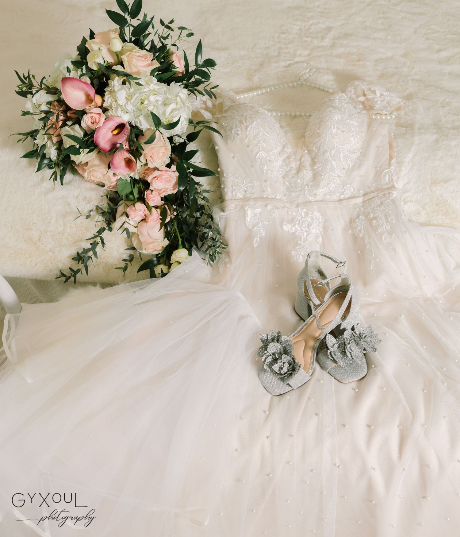 Elegant wedding details with white dress, silver shoes, and pink and white floral bouquet on white background.