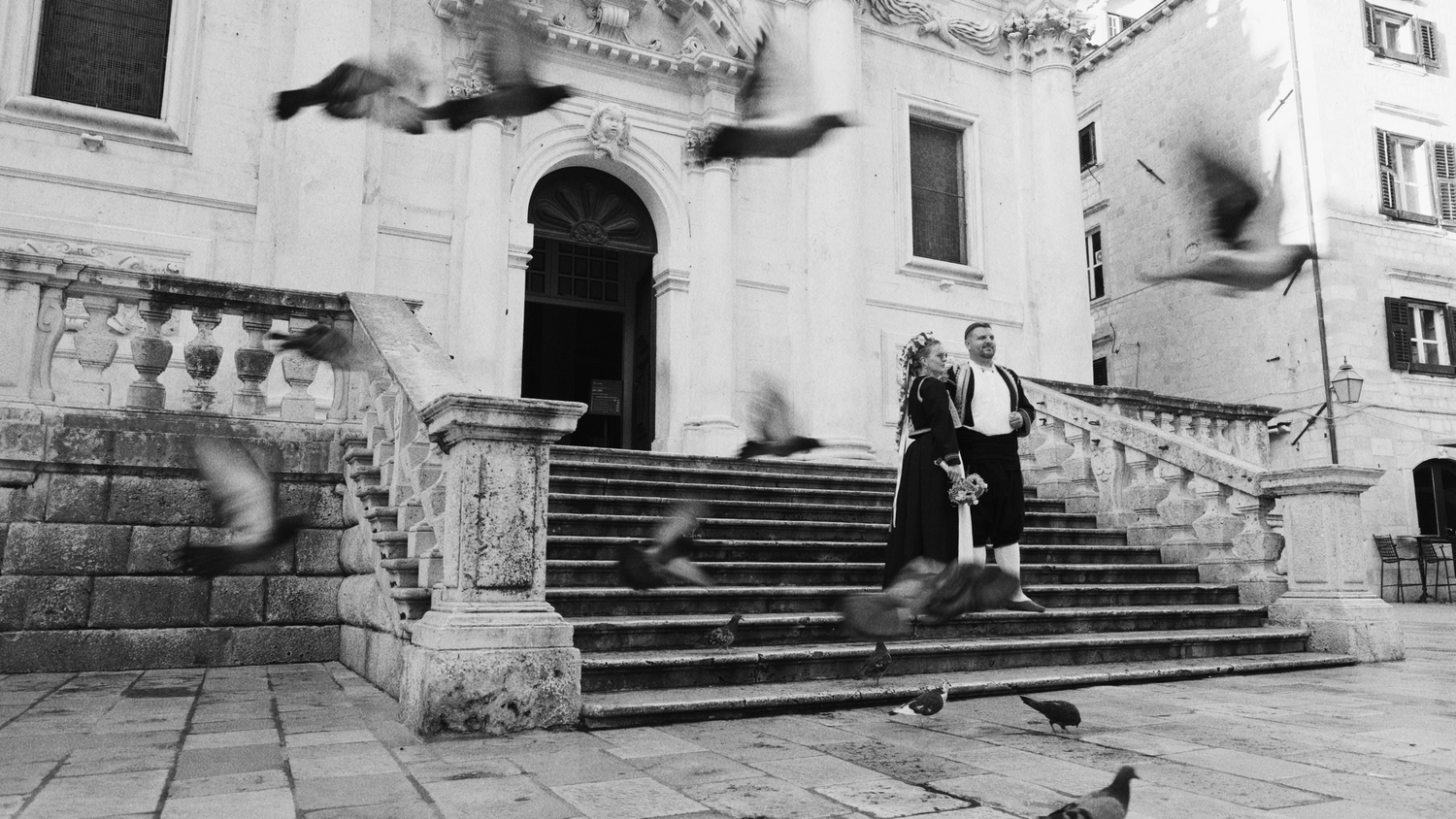 Vintage black and white photo of couple on grand stone steps with smoke effects.