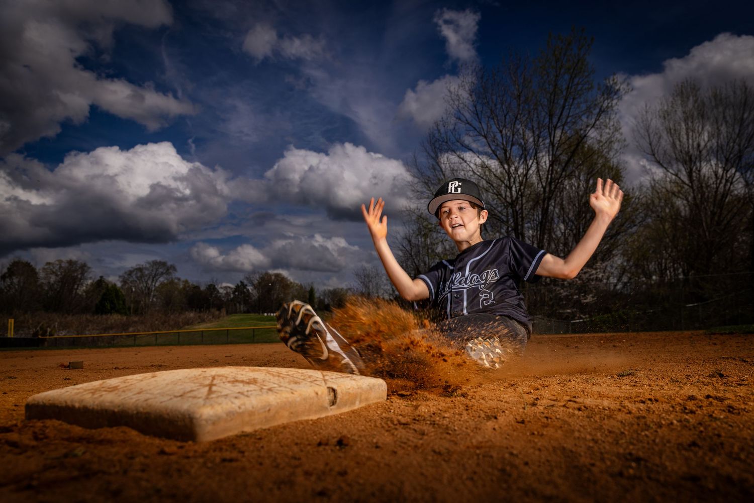Baseball players in action during a close play at second base on dirt infield.