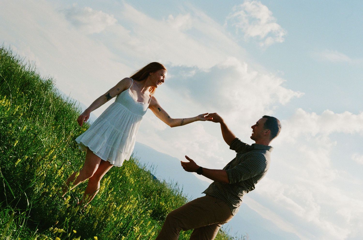 A couple shares an intimate moment at sunset on a golden hillside landscape.
