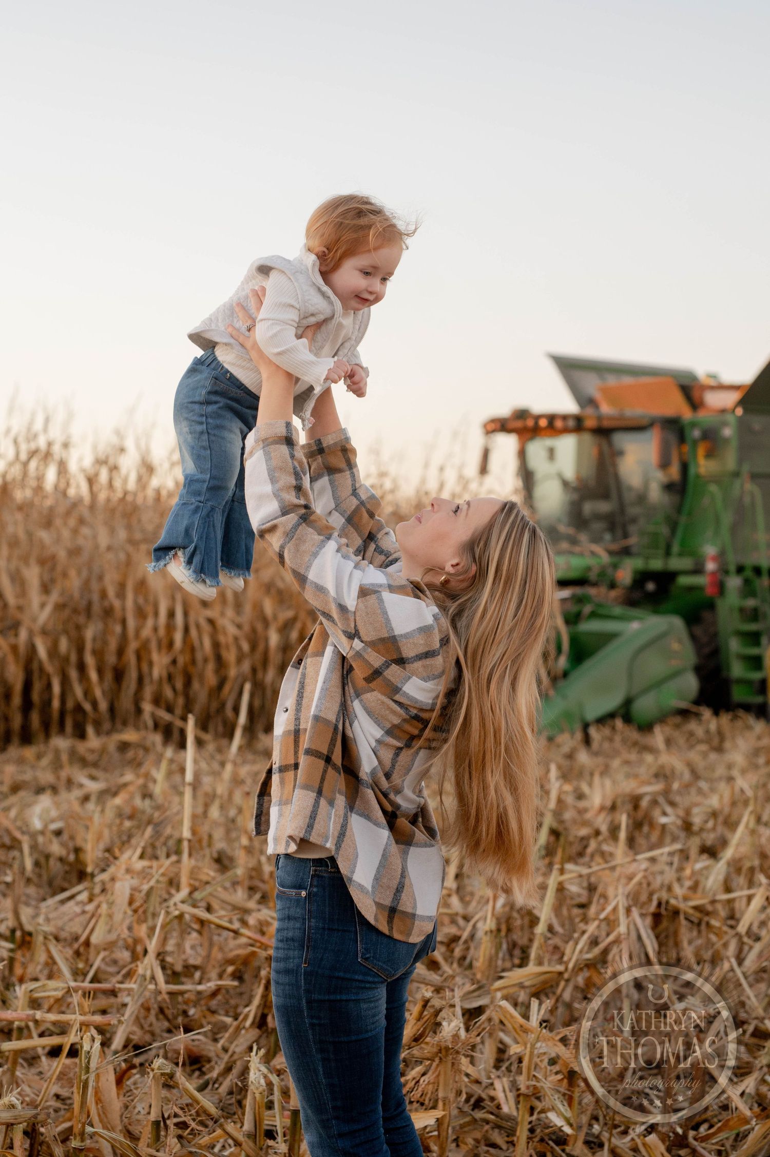 Joyful moment in a cornfield with a John Deere tractor in the background.
