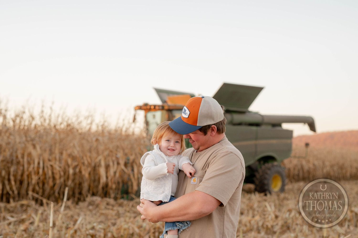 Tender embrace captured in a cornfield with farming equipment in background.