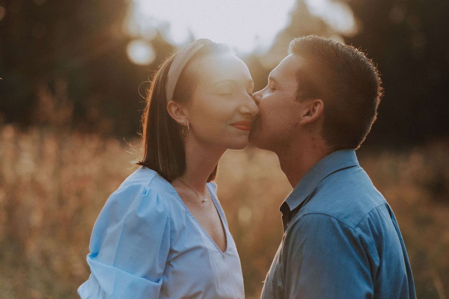 A tender moment between a couple sharing a kiss in golden sunset light.