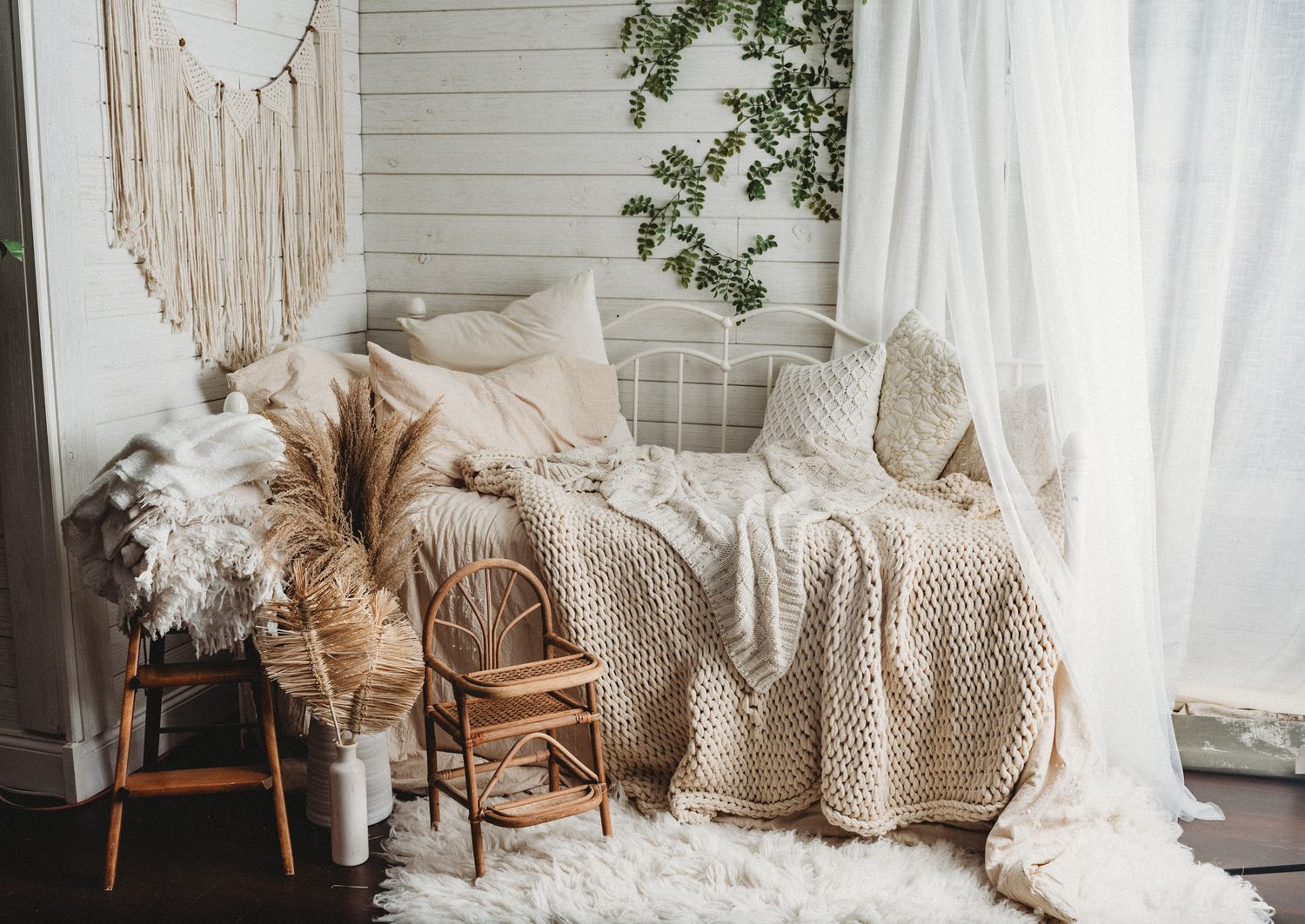 Cozy boho photography studio with cream daybed, macrame wall art, and neutral textured decor.