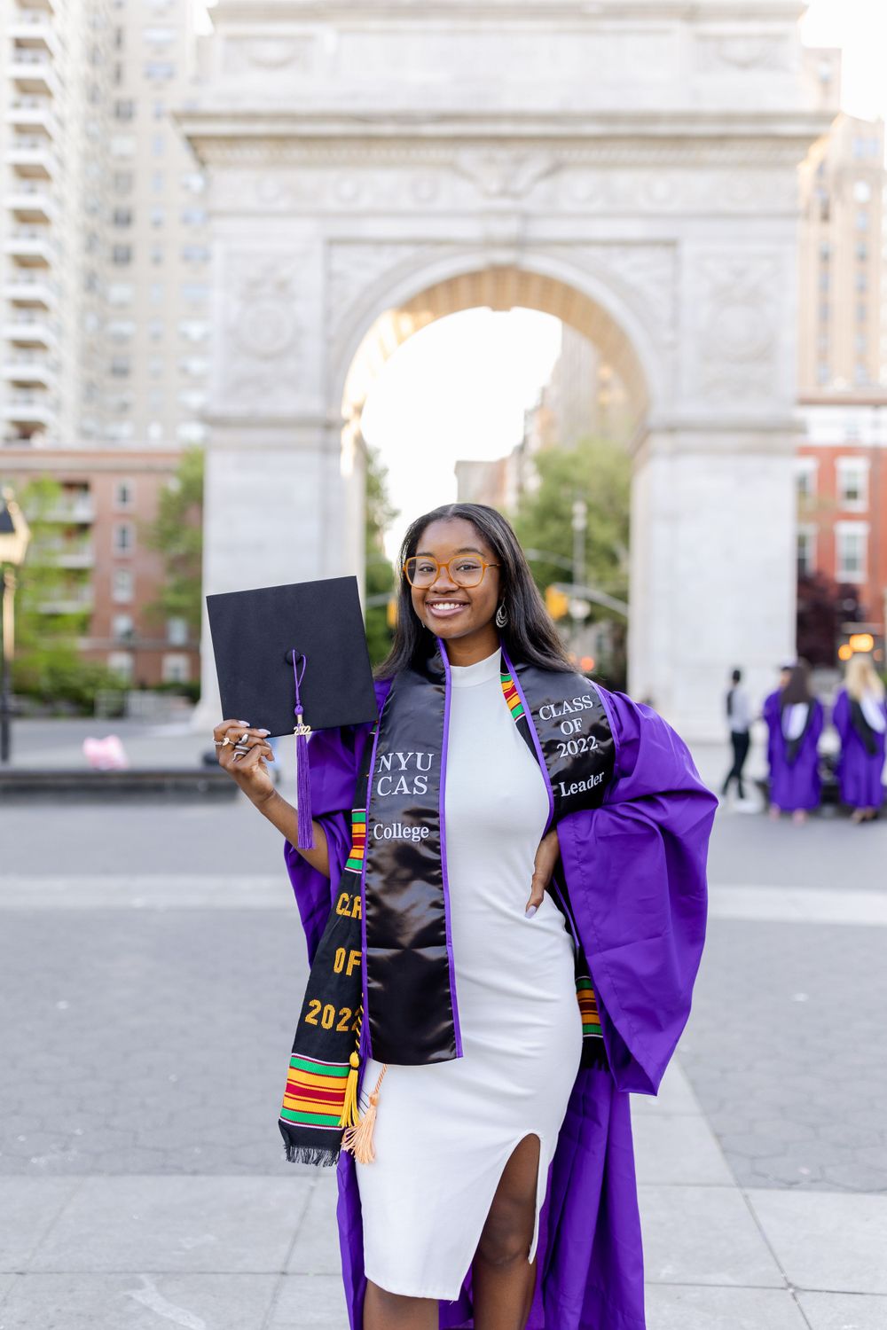 Graduate displays diploma while wearing purple graduation gown and decorated stole.