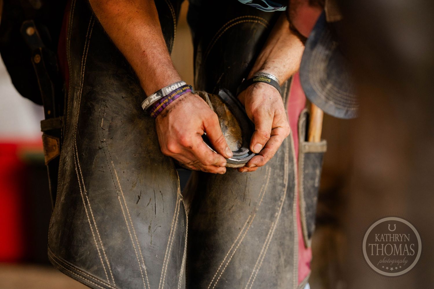 Detailed shot of hands working with horseshoe tools during farrier work.