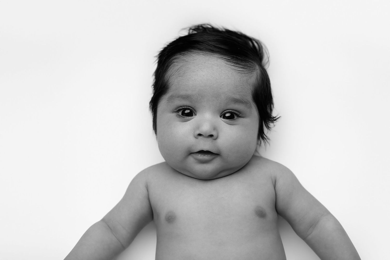 A black and white portrait of a chubby-cheeked baby against a light background.