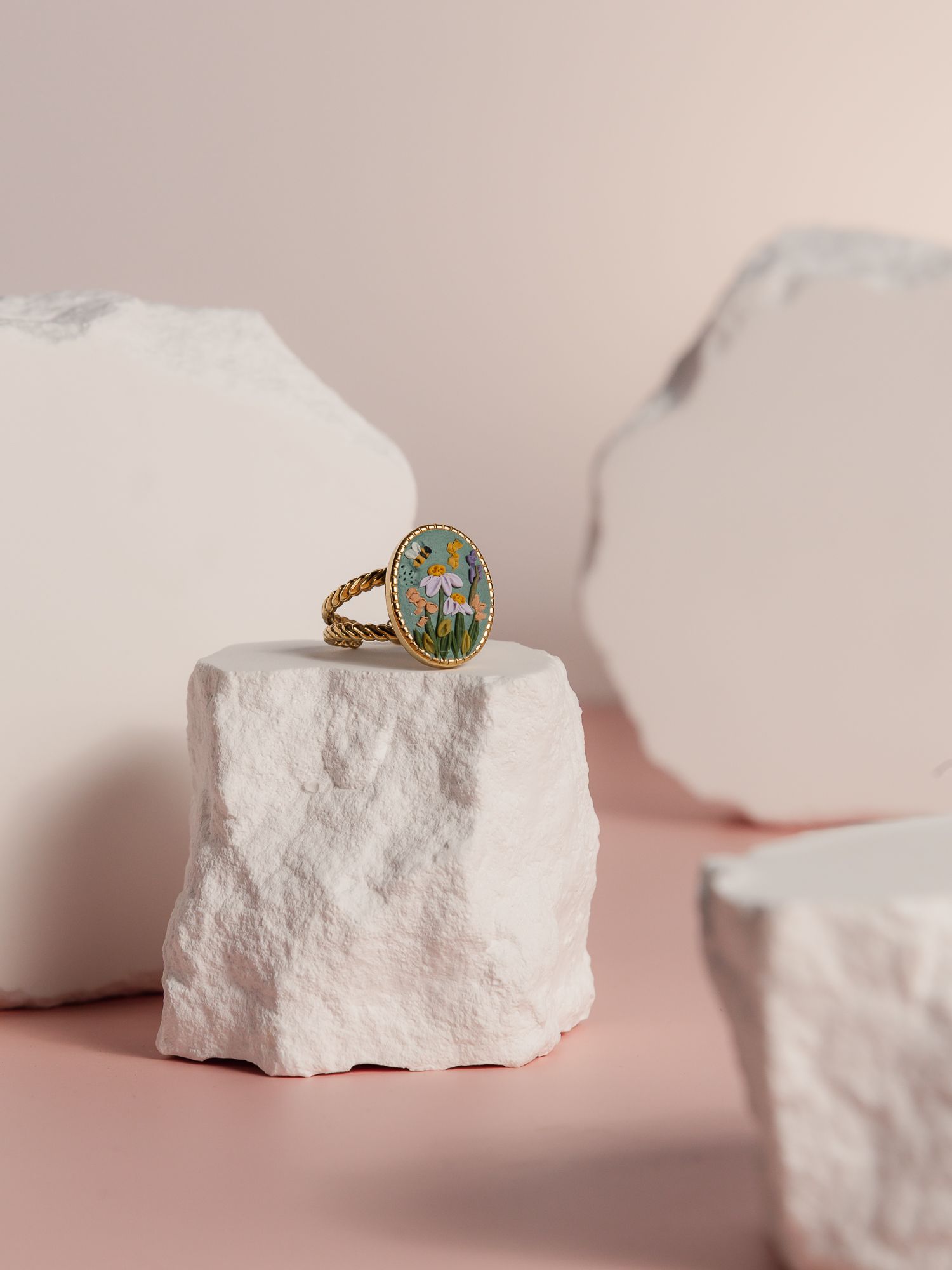 Gold rings displayed on white stone pedestals in minimalist product photography.