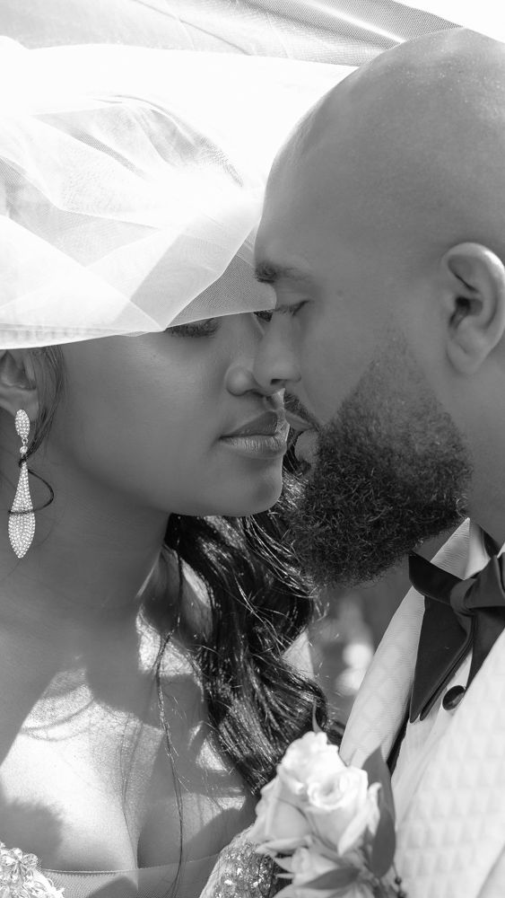 A tender black and white wedding portrait captures a romantic moment between newlyweds sharing an intimate kiss.