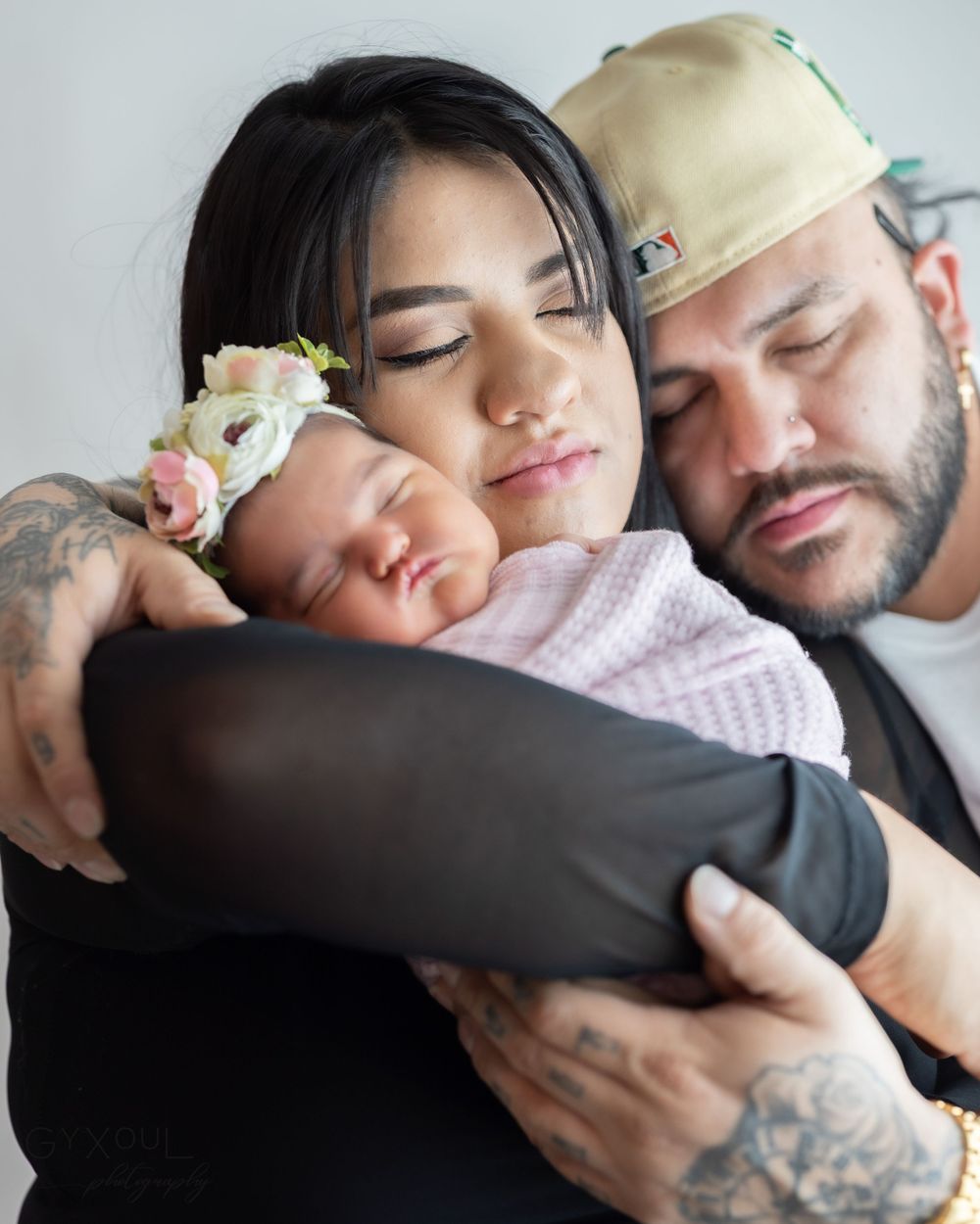 Peaceful family moment with sleeping newborn wearing floral crown.