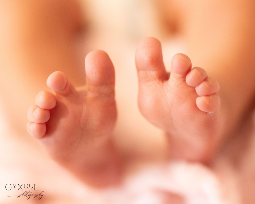 Close-up view of tiny baby feet against a soft peach-colored background.