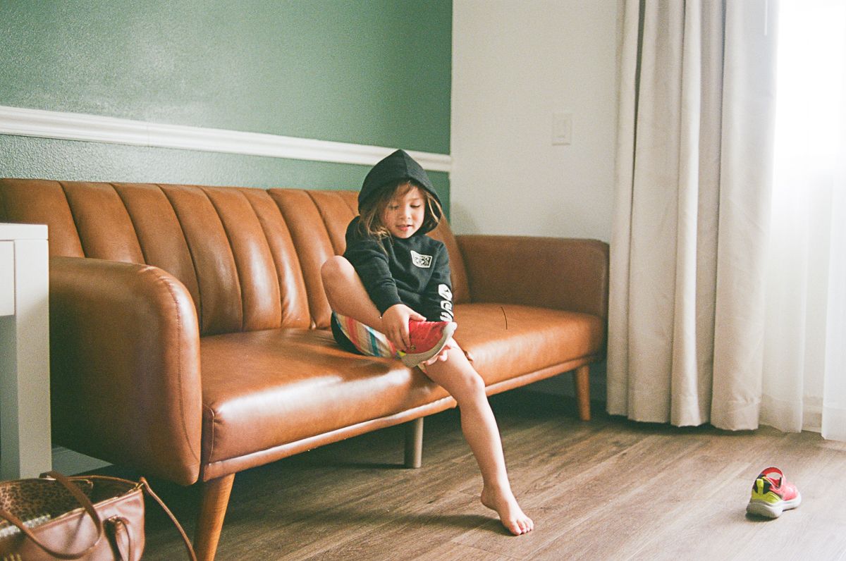 Minimalist interior scene with brown leather couch and green wall.