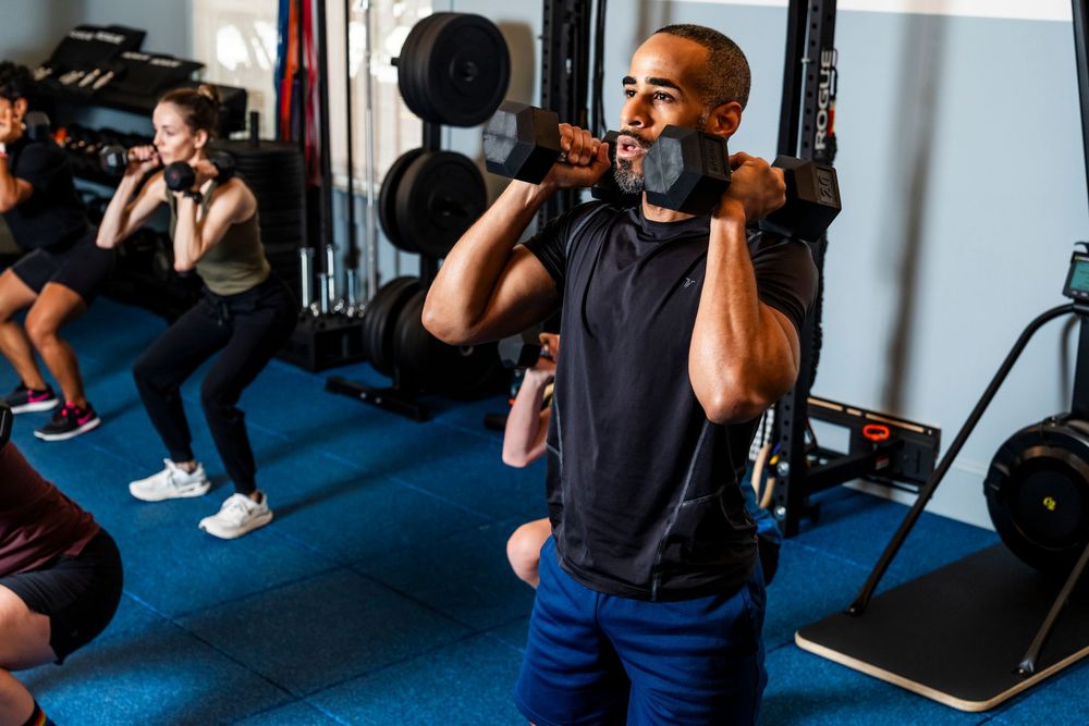 People exercising on gym equipment during a fitness class at a modern fitness facility.