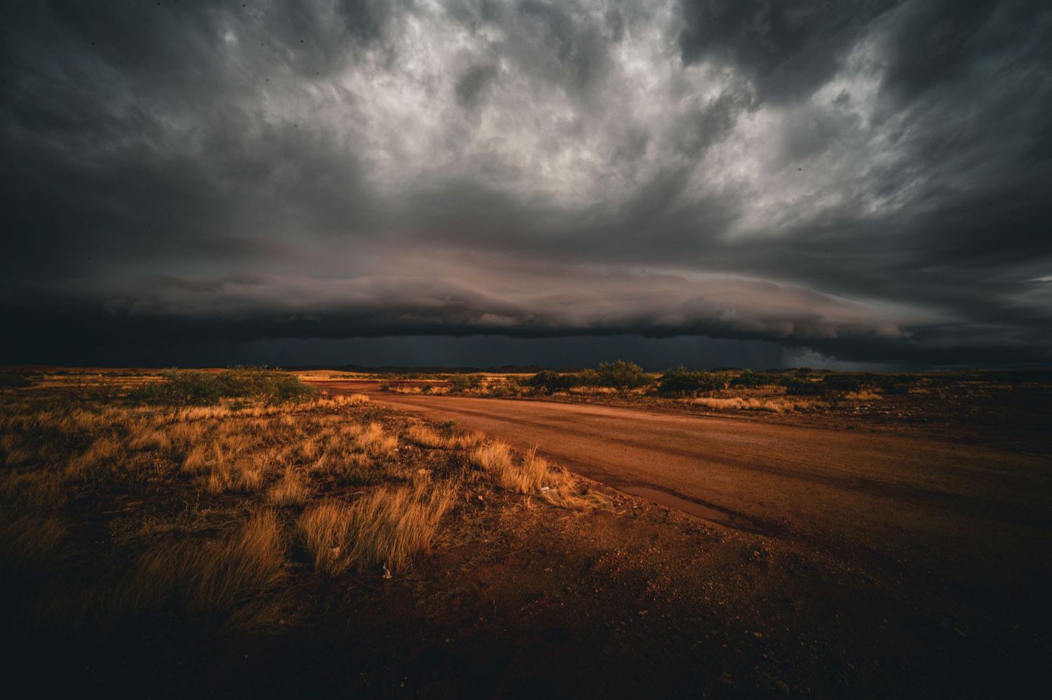 Dramatic storm clouds rolling over desert landscape at sunset with golden light.