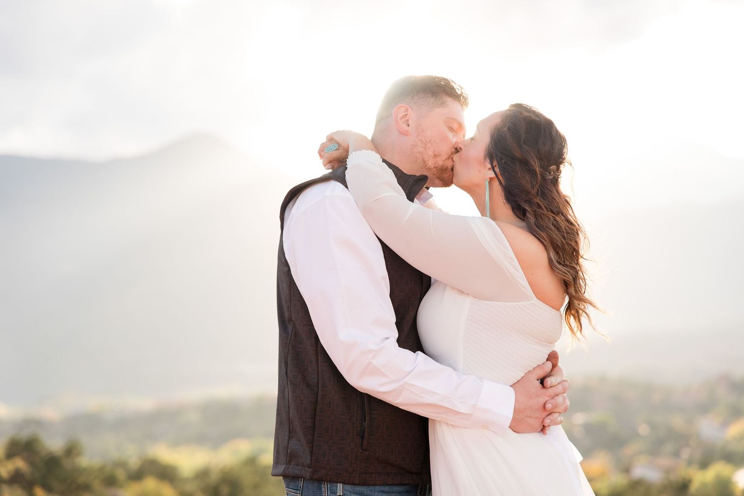 Romantic couple sharing a tender moment at sunset in casual outdoor attire.