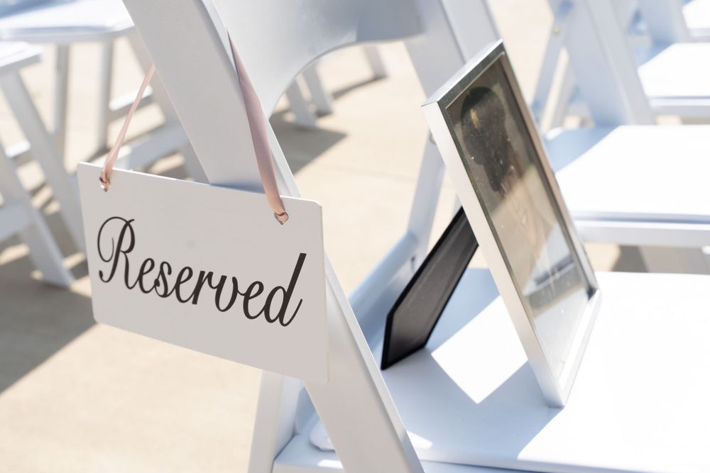 White folding chair with Reserved sign at wedding ceremony setup.