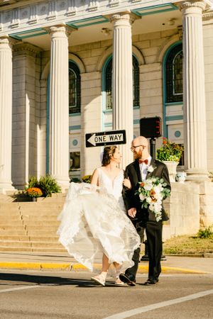 A wedding couple walking outside a grand historic building with white columns.