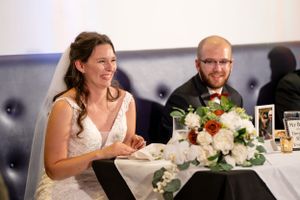 A wedding reception table set with elegant floral centerpieces and blue seating.